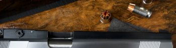 close up pistol gun barrel and wooden and dark black ground
