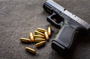 Close-Up Of Gun With Bullets On Table