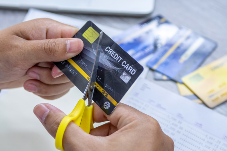 Man cutting credit card with scissors.