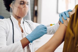 African American doctor injecting a Covid-19 vaccine to a female patient