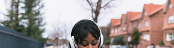 Multiracial girl listening to music and texting on the street, Woman messaging and listening to music on the street, Lifestyle woman concept on the street
