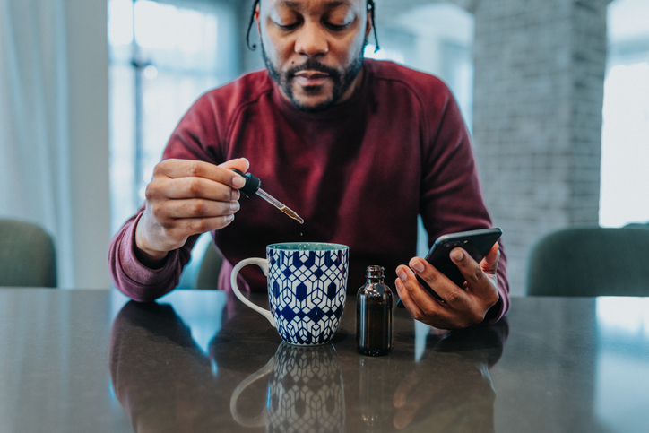 Man adding CBD oil to his herbal tea