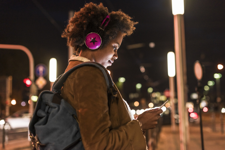 Afro woman with wireless headphones using tablet PC at street