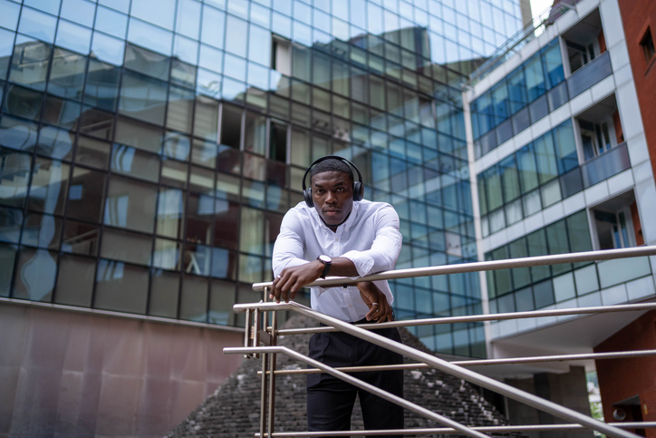 Young african american businessman leaning on railing outside office building