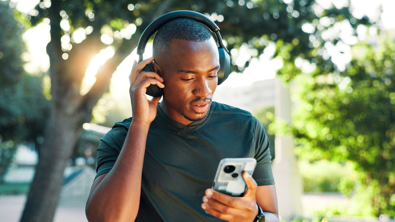 Nature, black man and fitness with mobile for headphones, podcast and confidence with audio track. Outdoor, male person and runner with music to listen, radio and smartphone with streaming exercise