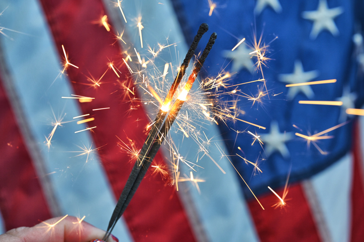 Holding a sparkler in front of an American Flag to celebrate the 4th of July Independence Day